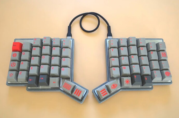 Photo of the Pando split keyboard, a grey and red keycap build with a USB-C cable joining the two halves